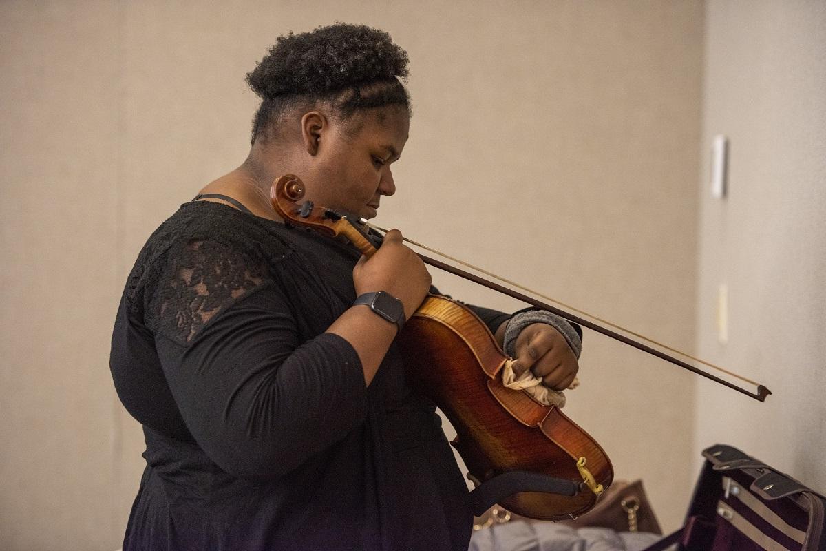 Image of a student cleaning their violin.